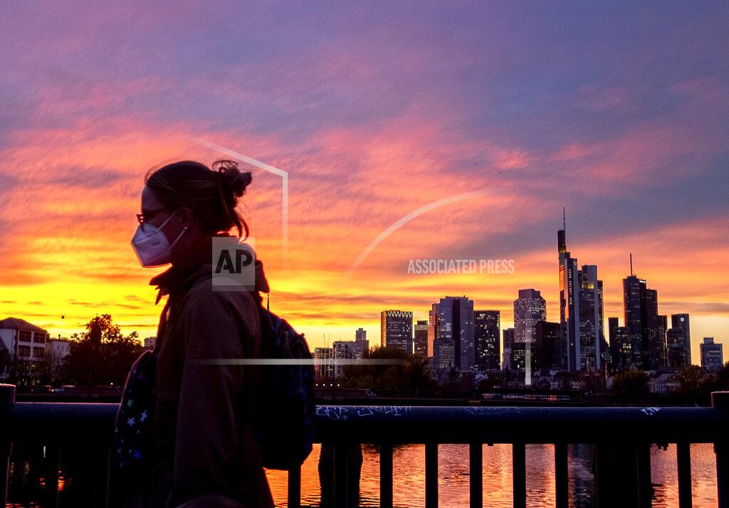 Michael Probst A woman wearing a face mask walks over a bridge with the buildings of the banking district in background in Frankfurt, Germany, Monday, Oct. 26, 2020. (AP Photo/Michael Probst)