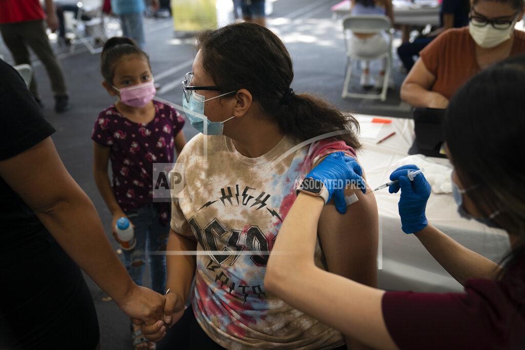 Jae C. Hong FILE - In this Aug. 28, 2021, file photo, holding her mother's hand, Brianna Vivar, 14, looks away while receiving the Pfizer COVID-19 vaccine from pharmacy technician Mary Tran at a vaccine clinic set up in the parking lot of CalOptima in Orange, Calif. The summer that was supposed to mark America’s independence from COVID-19 is instead drawing to a close with the U.S. more firmly under the tyranny of the virus, with deaths per day back up to where they were in March 2021. Legal disputes, threats and violence have erupted over mask and vaccine requirements. (AP Photo/Jae C. Hong, File)