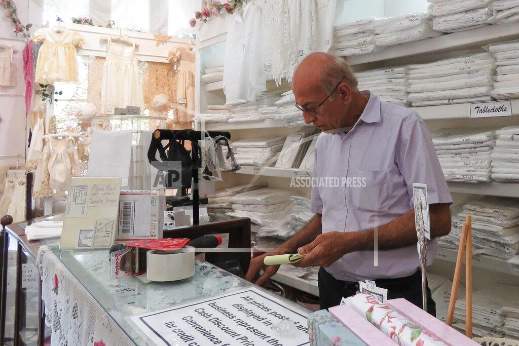 Janet Mcconnaughey Kichin Mirpuri, owner of Rendezvous Linen and Lace in New Oreans' French Quarter, works unmasked on Thursday, July 22, 2021, in New Orleans. He said he's vaccinated and washes his hands regularly, including any time he processes a customer's credit card. (AP Photo/Janet McConnaughey)