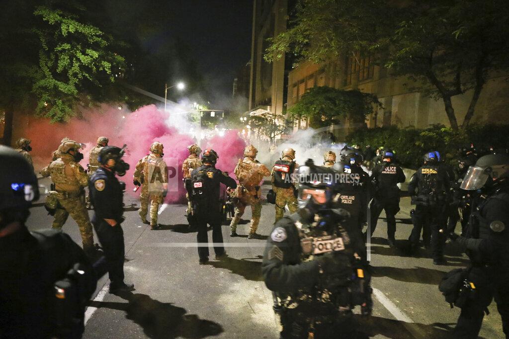 Dave Killen Police respond to protesters during a demonstration, Friday, July 17, 2020 in Portland, Ore. Militarized federal agents deployed by the president to Portland, fired tear gas against protesters again overnight as the city’s mayor demanded that the agents be removed and as the state’s attorney general vowed to seek a restraining order against them. (Dave Killen/The Oregonian via AP)