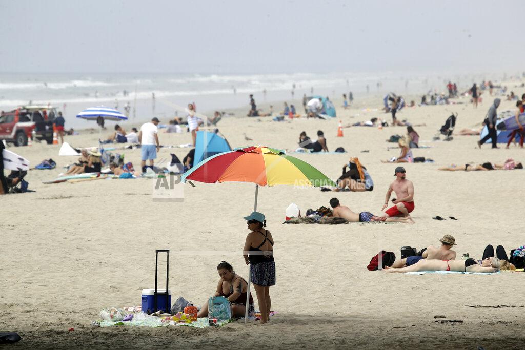 FILE - In this April 30, 2020 photo people crowd the beach in Huntington Beach, Calif. California Gov. Gavin Newsom’s administration gave approval Tuesday, May 5, to plans by Huntington Beach and two smaller cities to reopen beaches that fell under his order shutting down the entire Orange County coast after a heat wave drew large crowds to the shore. (AP Photo/Marcio Jose Sanchez, File)