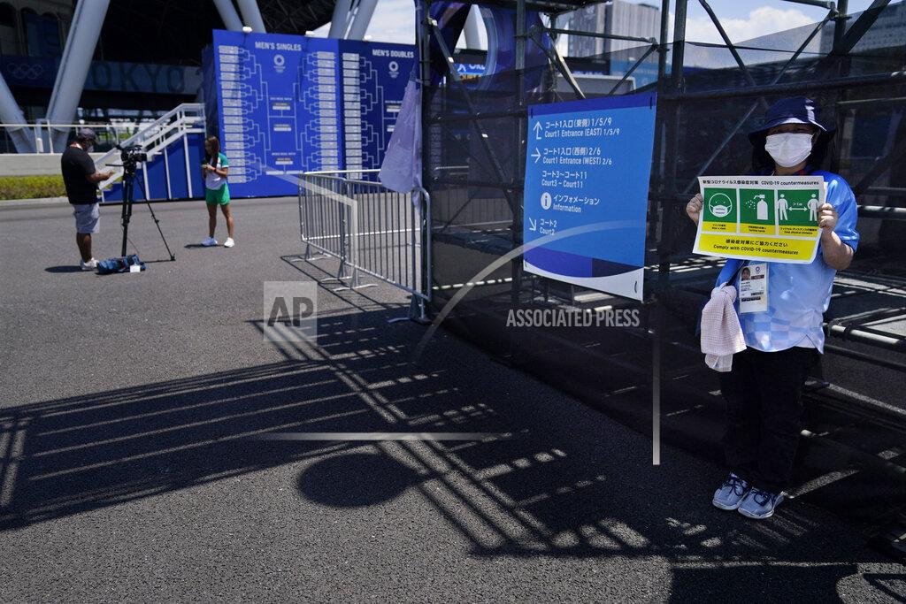 Seth Wenig FILE - In this July 24, 2021, file photo, a volunteer holds a sign warning people to keep their distance and wash their hands during the first round of the tennis competition at the 2020 Summer Olympics in Tokyo, Japan. (AP Photo/Seth Wenig, File)