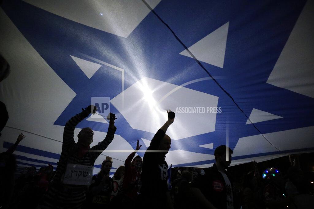 Sebastian Scheiner FILE - In this March. 20, 2021 file photo, Israeli protesters carry large Israeli flag during a demonstration against Israeli Prime Minister Benjamin Netanyahu In Jerusalem. Israel is holding its fourth election in two years after two deadlocked votes and a government that collapsed after less than a year. It is widely seen as a one-issue referendum — with the electorate almost evenly divided — on whether longtime Prime Minister Benjamin Netanyahu can remain in power. (AP Photo/Sebastian Scheiner, File)
