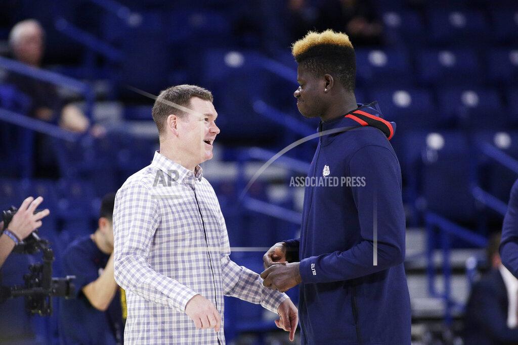 Young Kwak FILE - In this Nov. 5, 2019, file photo, Gonzaga assistant coach Tommy Lloyd, left, and academic redshirt Oumar Ballo, of Mali, speak before an NCAA college basketball game against Alabama State in Spokane, Wash. Lloyd’s passports is rich with stamps. In his 19th season as Few’s top assistant at second-ranked Gonzaga, Lloyd has become the conduit for the Zags’ international expansion. (AP Photo/Young Kwak, File)