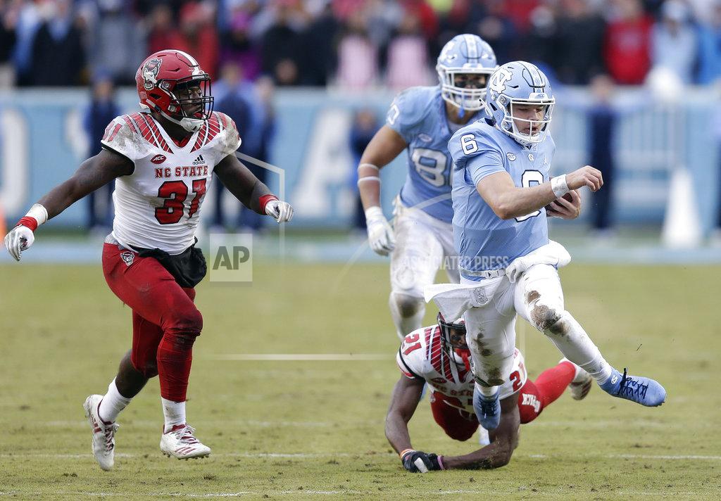 Gerry Broome North Carolina quarterback Cade Fortin (6) runs the ball as North Carolina State's Jarius Morehead (31) and Stephen Griffin (21) chase during the first half of an NCAA college football game in Chapel Hill, N.C., Saturday, Nov. 24, 2018. (AP Photo/Gerry Broome)