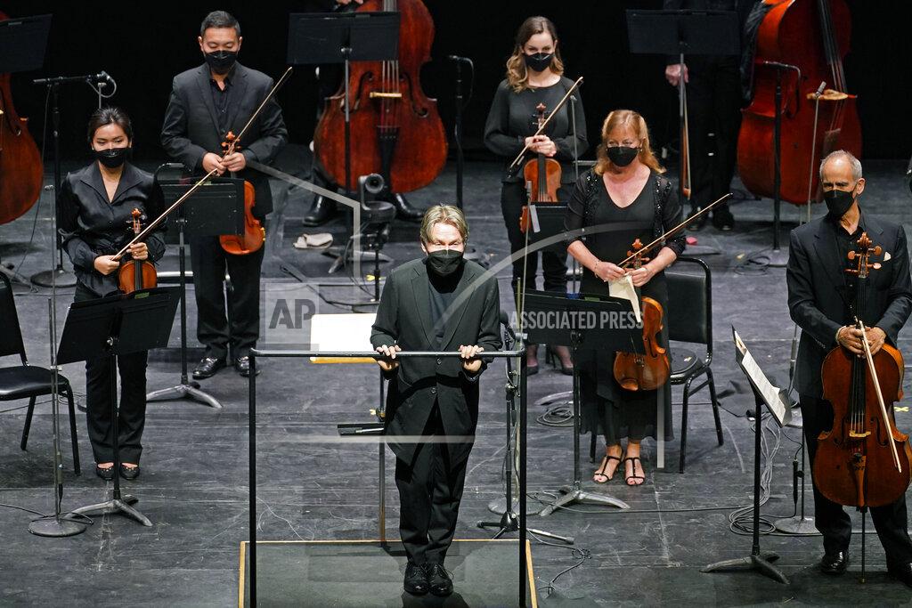 Guest conductor Esa Pekka Salonen, front center, greets a live audience as New York Philharmonic musicians stand behind him before they performed together for the first time since March 10, 2020, at The Shed in Hudson Yards, Wednesday, April 14, 2021, in New York. Normal subscription performances are scheduled to resume in September. (AP Photo/Kathy Willens)