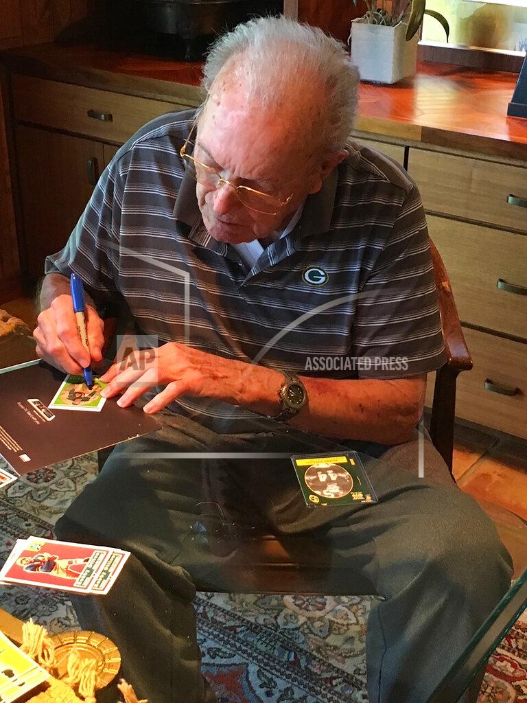 Uncredited In this June 2019 photo provided by Karen Gooch, former Green Bay Packers football player Bobby Dillon autographs football cards at his home in Temple, Texas. Dillon was one of the best defensive players in the league. But the Packers were an NFL weakling at the time, going 33-61-2 while Dillon was playing safety so well he made four All-Pro teams and intercepted 52 passes. Dillon passed away at age 89 in August 2019, five months before he was selected for the Hall of Fame as part of the centennial class. (Karen Gooch via AP)