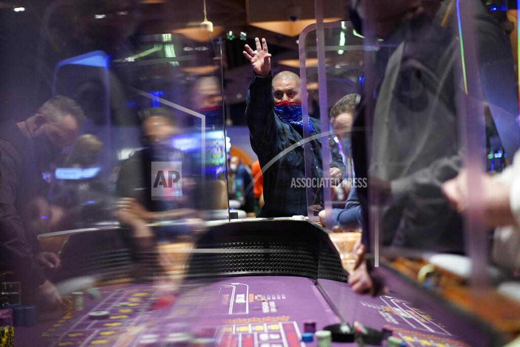 John Locher People play craps while wearing masks and between plexiglas partitions as a precaution against the coronavirus at the opening night of the Mohegan Sun Casino at Virgin Hotels Las Vegas, Thursday, March 25, 2021, in Las Vegas. The casino opened at the former Hard Rock Hotel property. (AP Photo/John Locher)