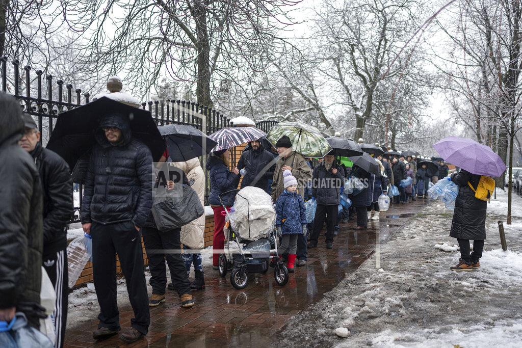Evgeniy Maloletka People line up to collect water, in Kyiv, Ukraine, Thursday, Nov. 24, 2022. Residents of Ukraine's bombed but undaunted capital clutched empty bottles in search of water and crowded into cafés for power and warmth Thursday, switching defiantly into survival mode after new Russian missile strikes a day earlier plunged the city and much of the country into the dark. (AP Photo/Evgeniy Maloletka)