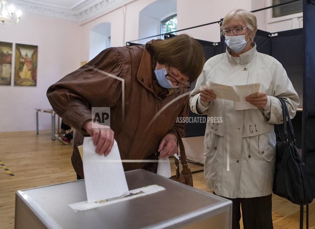 Mindaugas Kulbis A Lithuanian woman, wearing face masks to protect against coronavirus cast their ballots at a polling station during parliamentary elections in Vilnius, Lithuania, Sunday, Oct. 11, 2020. Polls opened Sunday for the first round of national election in Lithuania, where voters will renew the 141-seat parliament and the ruling four-party coalition is widely expected to face a stiff challenge from the opposition to remain in office. (AP Photo/Mindaugas Kulbis)