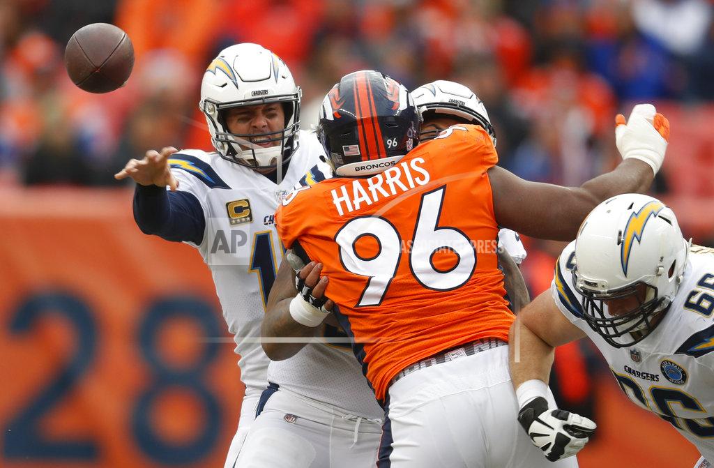 Los Angeles Chargers quarterback Philip Rivers, left, throws a pass under pressure from Denver Broncos defensive end Shelby Harris (96) during the first half of an NFL football game, Sunday, Dec. 30, 2018, in Denver. (AP Photo/David Zalubowski)