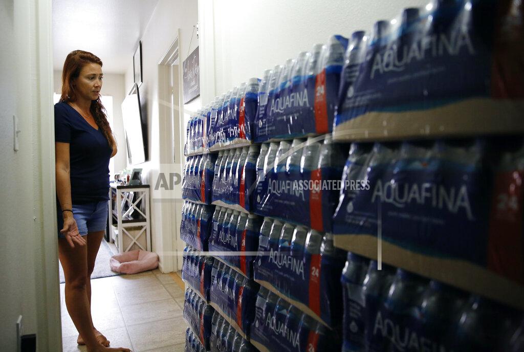Caleb Jones Lauren Wright, a Navy spouse whose family was sickened by jet fuel in their tap water, shows her supply of bottled water at her home in Honolulu, Friday, July 1, 2022. A Navy investigation says shoddy management and human error caused fuel to leak into Pearl Harbor's tap water last year. The leak poisoned thousands of people and forced military families to evacuate their homes for hotels. (AP Photo/Caleb Jones)
