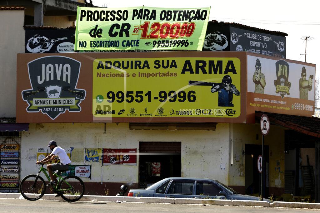 Eraldo Peres Advertisments promote the sales of armed weapons with one banner reading in Portuguese: "Get your weapon here," in Luziania, Brazil, Thursday, March 4, 2021. Brazilian President Jair Bolsonaro is pushing to deliver on his promise to arm every person that wants it. (AP Photo/Eraldo Peres)