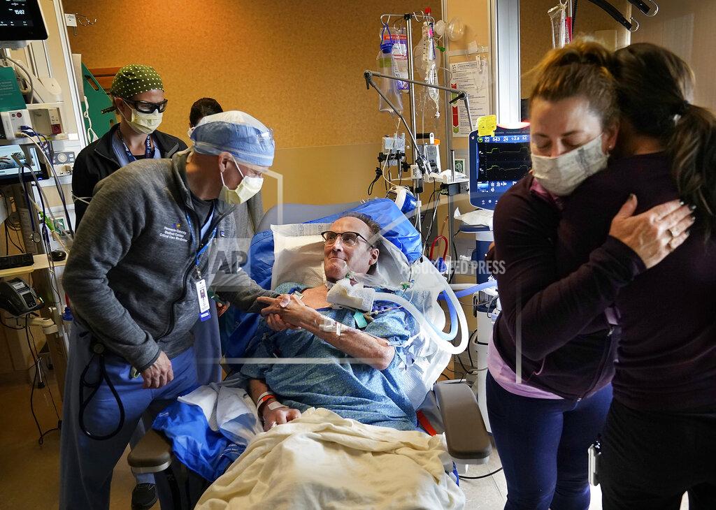 David Joles Dr. Mark Sprenkle, left, shakes hands with John Grubb as Grubb's wife Kelly, second from right, says goodbye to other HCMC caregivers before Grubb was discharged from HCMC Monday, May 3, 2021 in Minneapolis. Grubb, of St. Michael, was discharged from HCMC after 81 days on the ECMO heart-lung bypass machine. ECMO has been the treatment of last resort in COVID-19 care, saving 50% of people when used globally, but has been a critical tool when doctors run out of options for severely ill patients. (David Joles/Star Tribune via AP)
