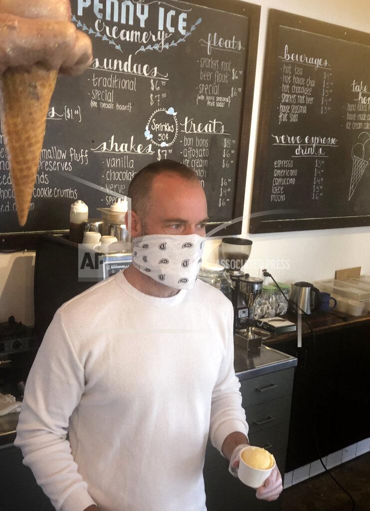 Martha Mendoza Wearing a protective mask Zachary Davis, serves up a scoop of ice cream at his shop The Penny Ice Creamery in Santa Cruz, Calif., Friday, April 17, 2020. Davis, who owns two ice cream parlors, a beachside cafe and a taco bar in Santa Cruz, has had to lay off 70 employees due to the coronavirus outbreak. (AP Photo/Martha Mendoza)