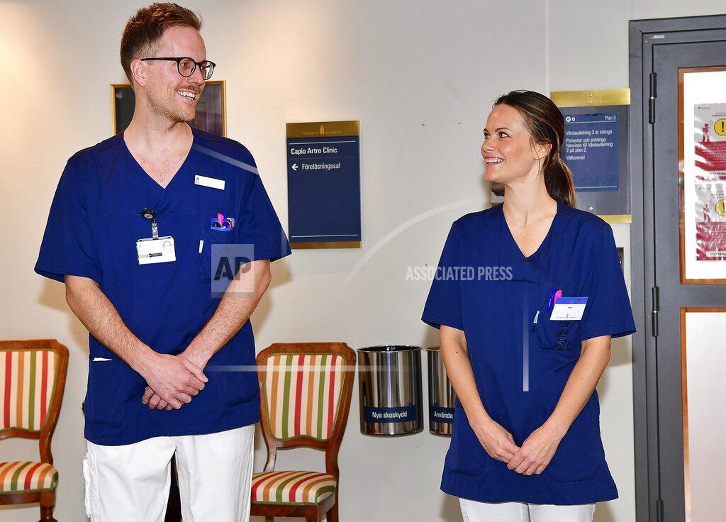 Jonas Ekstromer/Tt In this photo taken on Thursday, April 16, 2020, Sweden's Princess Sofia poses for the media next to registered nurse Gustav Westoo, on her first day at work at Sophiahemmet hospital, of which she is the patron, in Stockholm. The Princess has completed an intensive training program and will now be able to assist hospital staff with non-medical related tasks during the coronavirus pandemic. (Jonas Ekstromer/TT News Agency via AP)