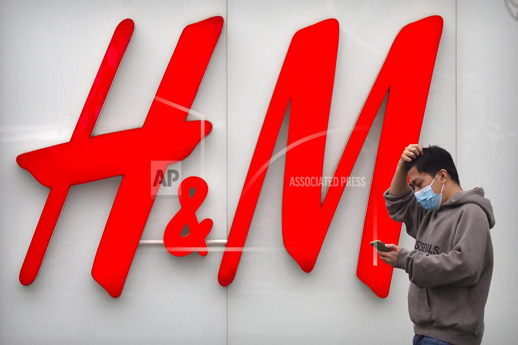 Mark Schiefelbein A man uses his smartphone as he walks past an H&M clothing store at a shopping mall in Beijing, Friday, March 26, 2021. H&M disappeared from the internet in China as the government raised pressure on shoe and clothing brands and announced sanctions Friday against British officials in a spiraling fight over complaints of abuses in the Xinjiang region. (AP Photo/Mark Schiefelbein)