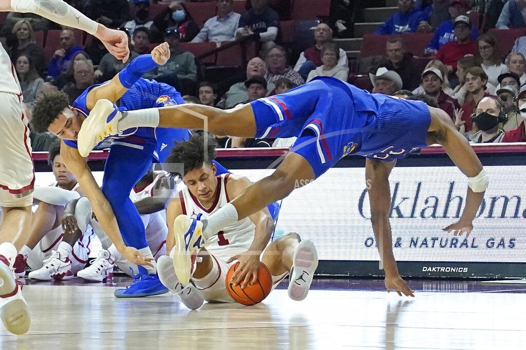 Sue Ogrocki Kansas forward David McCormack, right, dives over Oklahoma forward Jalen Hill (1) in front of teammate forward Jalen Wilson, left, in the first half of an NCAA college basketball game Tuesday, Jan. 18, 2022, in Norman, Okla. (AP Photo/Sue Ogrocki)