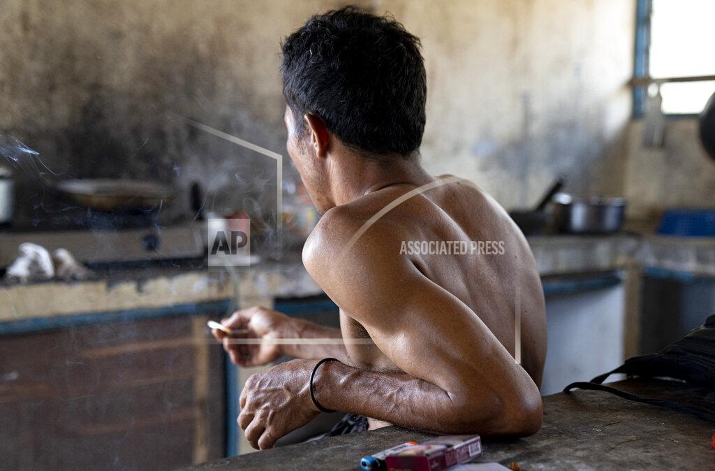 Ore Huiying An Indonesian migrant worker rests after working on a palm oil plantation run by the government-owned Felda in Malaysia, in early 2020. Jum, a former worker who escaped from this same plantation, described to The Associated Press how the company confiscated, described sleeping on the ground, exposed to the wind and monsoon rains, with only a campfire to fend off snakes and tigers. (AP Photo/Ore Huiying)