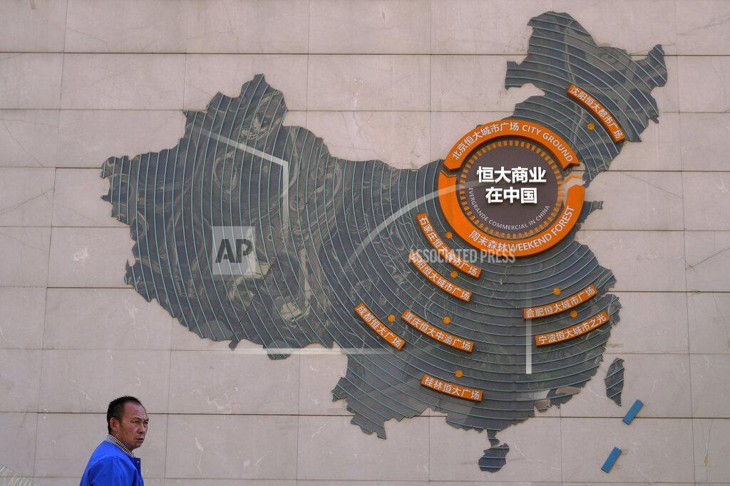 Andy Wong A custodian stands near a map showing Evergrande development projects in China on a wall in an Evergrande city plaza in Beijing, Tuesday, Sept. 21, 2021. Global investors are watching nervously as the Evergrande Group, one of China's biggest real estate developers, struggles to avoid defaulting on tens of billions of dollars of debt, fueling fears of possible wider shock waves for the Chinese financial system. (AP Photo/Andy Wong)