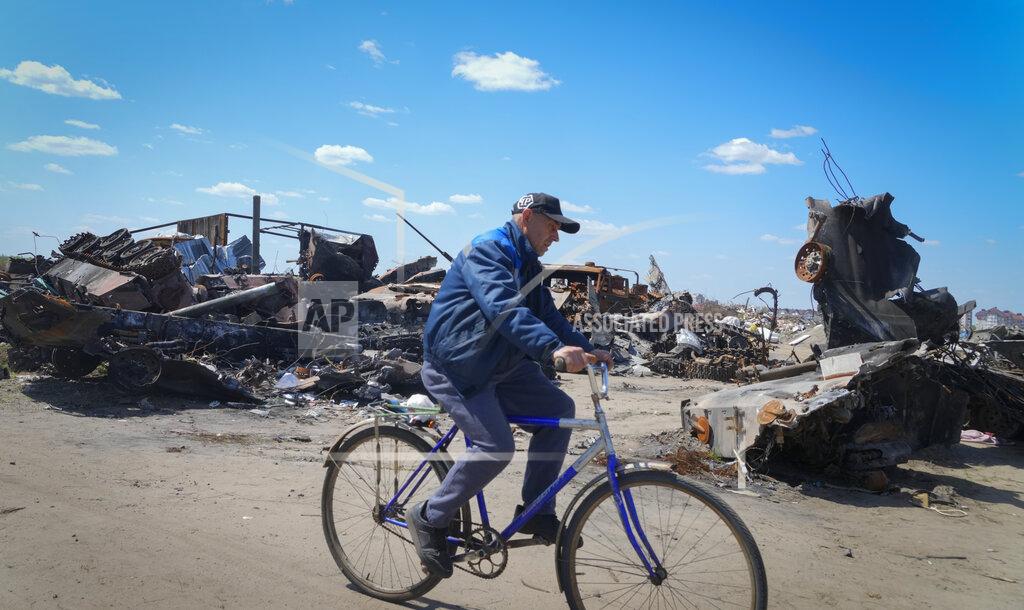 Efrem Lukatsky A local residence rides a bike past a destroyed Russian military vehicle in Bucha, on the outskirts of Kyiv, Ukraine, Tuesday, May 10, 2022. (AP Photo/Efrem Lukatsky)