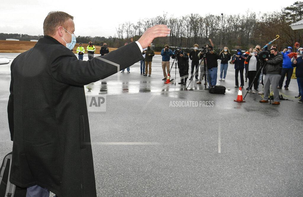 Todd Van Emst In this photo provided by Auburn Athletics, Bryan Harsin, left, Auburn's new football coach, is greeted at an airport Thursday, Dec. 24, 2020, in Auburn, Ala. (Todd Van Emst/Auburn Athletics via AP)
