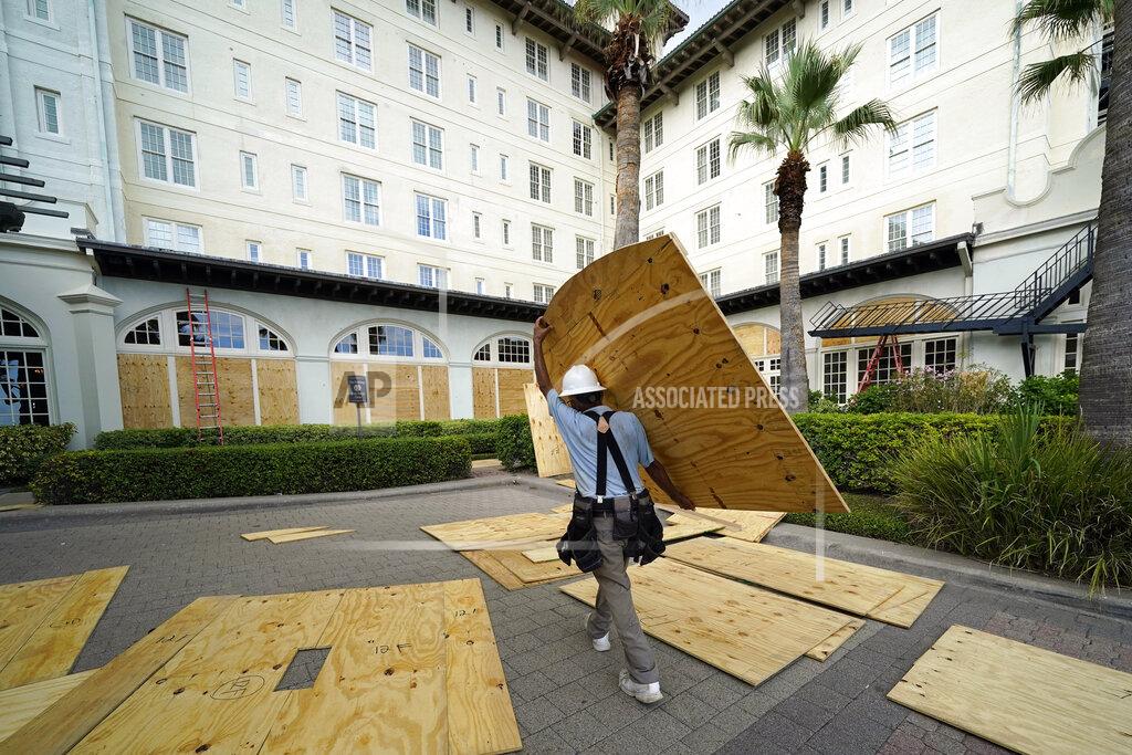 David J. Phillip Workers board up windows at the Galvez Hotel & Spa Tuesday, Aug. 25, 2020, in Galveston, Texas, as Hurricane Laura heads toward the Gulf Coast. (AP Photo/David J. Phillip)