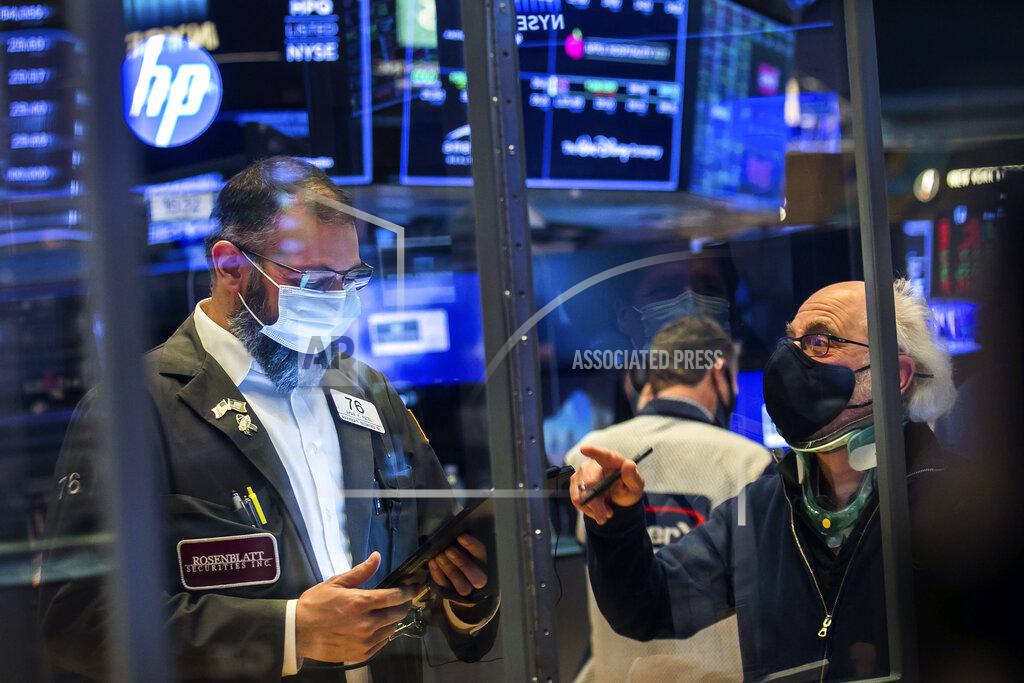 In this photo provided by the New York Stock Exchange, traders Aman Patel, left, and Peter Tuchman work on the floor, Friday, Feb 26, 2021. Stocks wobbled between small gains and losses on Wall Street Friday as rising technology stocks offset a slide in banks and energy companies. (Courtney Crow/New York Stock Exchange via AP)