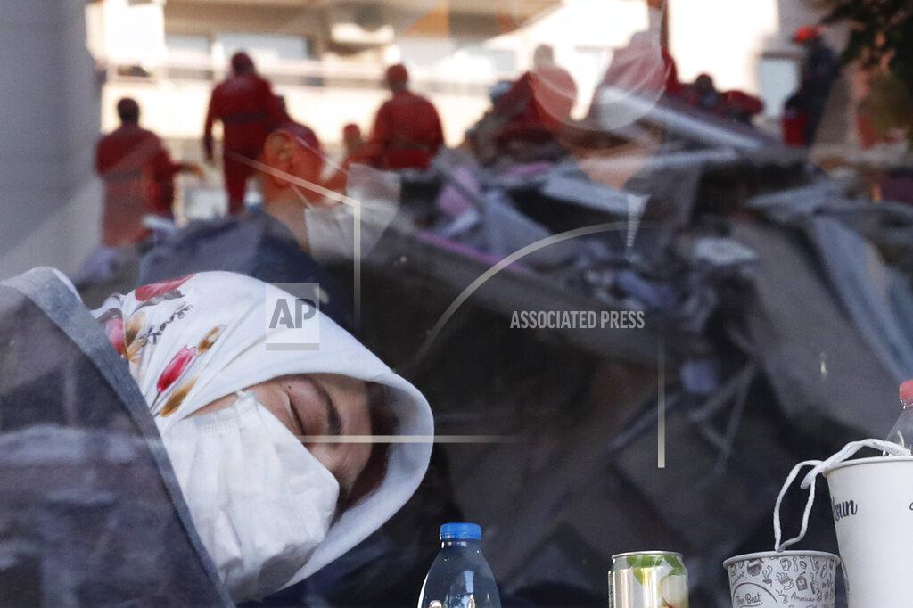 Darko Bandic A local resident, staying outdoors for fear of aftershocks, takes.a moment to relax inside a coffee shop, as members of rescue services searching for survivors in the debris of a collapsed building are reflected in the window, in Izmir, Turkey, early Saturday, Oct. 31, 2020. Rescue teams on Saturday ploughed through concrete blocs and debris of eight collapsed buildings in Turkey's third largest city in search of survivors of a powerful earthquake that struck Turkey's Aegean coast and north of the Greek island of Samos, killing dozens Hundreds of other were injured. (AP Photo/Darko Bandic)
