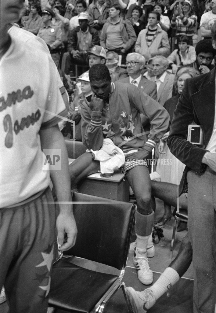 Anonymous FILE - In this April 5, 1983, file photo, University of Houston's Akeem Olajuwon sits after the last second shot by Lorenzo Charles of North Carolina State won the Final Four championship game game in Albuquerque, N.M. The NCAA and networks across the sports dial have infused fans with a hoops fix by rebroadcasting epic NCAA Tournament games. Coaches and players involved in those games are adding insight and a dash of humor by live tweeting during the replay. (AP Photo/File)