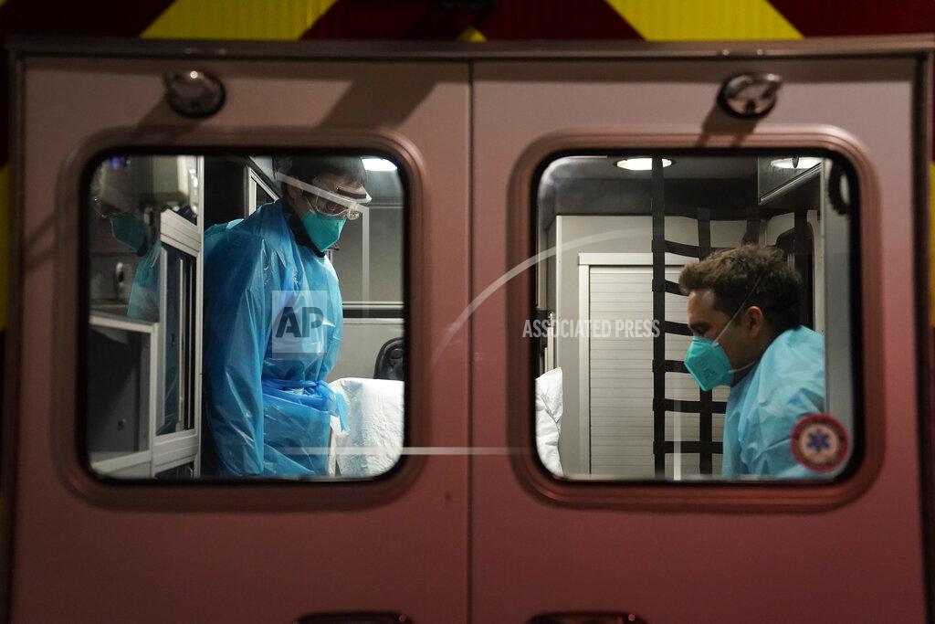 Emergency medical technician Thomas Hoang, left, of Emergency Ambulance Service, and paramedic Trenton Amaro prepare to unload a COVID-19 patient from an ambulance in Placentia, Calif., Friday, Jan. 8, 2021. EMTs and paramedics have always dealt with life and death — they make split-second decisions about patient care, which hospital to race to, the best and fastest way to save someone — and now they're just a breath away from becoming the patient themselves. (AP Photo/Jae C. Hong)