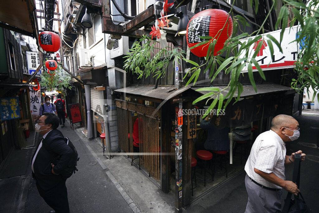 Eugene Hoshiko Men wearing protective masks to help curb the spread of the new coronavirus stand at a back ally bar street in Tokyo Friday, June 26, 2020. Japan lifted a seven-week pandemic state emergency in late May, and social and business activity have since largely resumed. (AP Photo/Eugene Hoshiko)