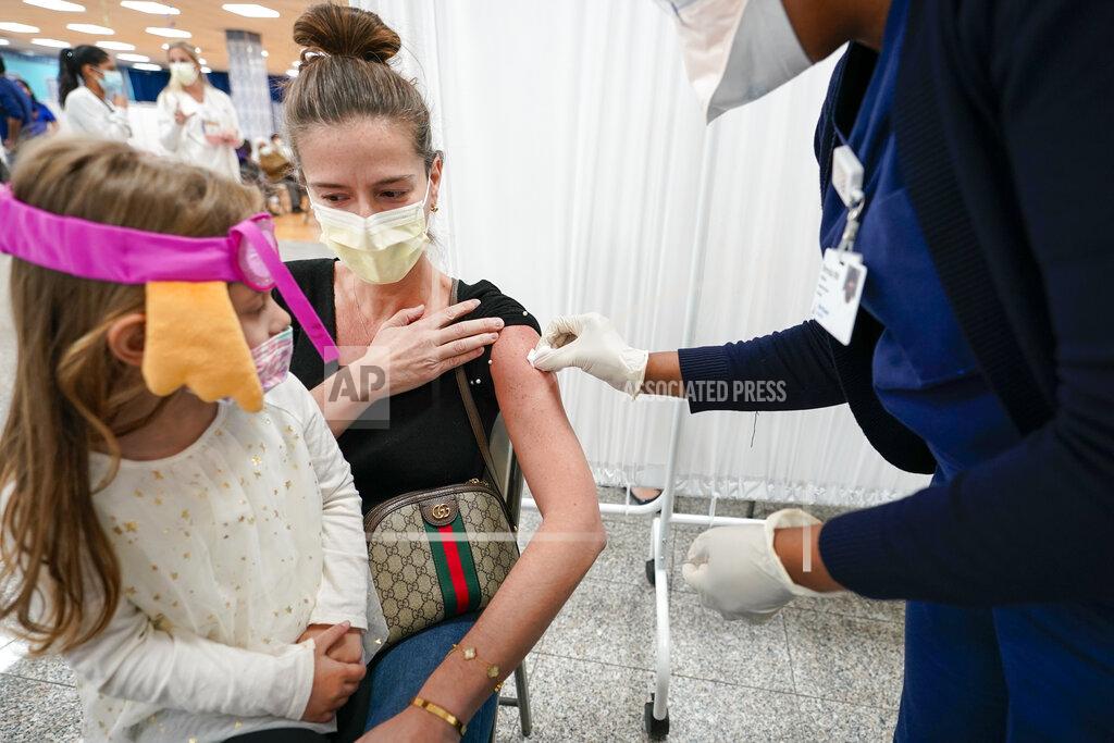 Mosque member Asie Late's granddaughter Emma watches as a Northwell Health registered nurse inoculates her with the Johnson & Johnson COVID-19 vaccine at a pop up vaccination site inside the Albanian Islamic Cultural Center, Thursday, April 8, 2021, in the Staten Island borough of New York. (AP Photo/Mary Altaffer)
