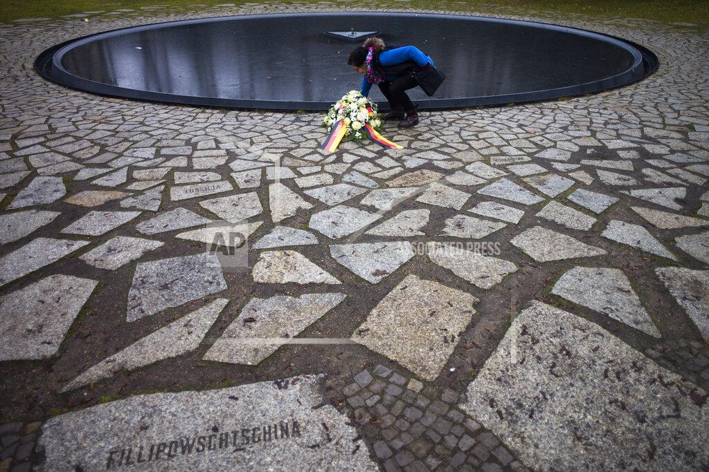 Markus Schreiber A woman adjust flowers at the Memorial to the Sinti and Roma Victims of the Holocaust on the International Holocaust Remembrance Day, in Berlin, Germany, Wednesday,, Jan. 27, 2021. (AP Photo/Markus Schreiber)
