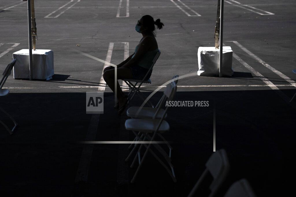Jae C. Hong FILE - In this Aug. 28, 2021, file photo, a woman waits in the holding area after receiving the COVID-19 vaccine at a clinic set up in the parking lot of CalOptima in Orange, Calif. California is seeing lower coronavirus transmission than other U.S. states as virus cases and hospitalizations decline following a summer surge. State health experts say relatively high vaccination rates ahead of the arrival of the delta variant made a difference. (AP Photo/Jae C. Hong, File)