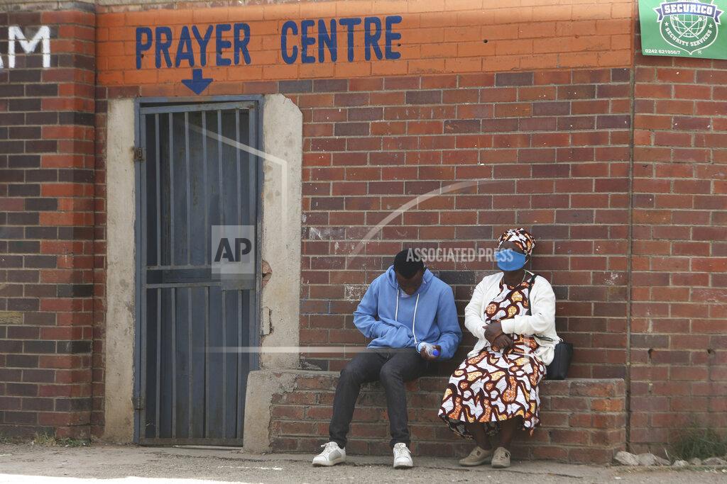 People are seen outside a prayer centre in Harare, Thursday May 28, 2020. Manhunts have begun after hundreds of people, some with the coronavirus, fled quarantine centres in Zimbabwe and Malawi while authorities worry they will spread COVID-19 in countries whose health systems can be rapidly overwhelmed.(AP Photo/Tsvangirayi Mukwazhi)