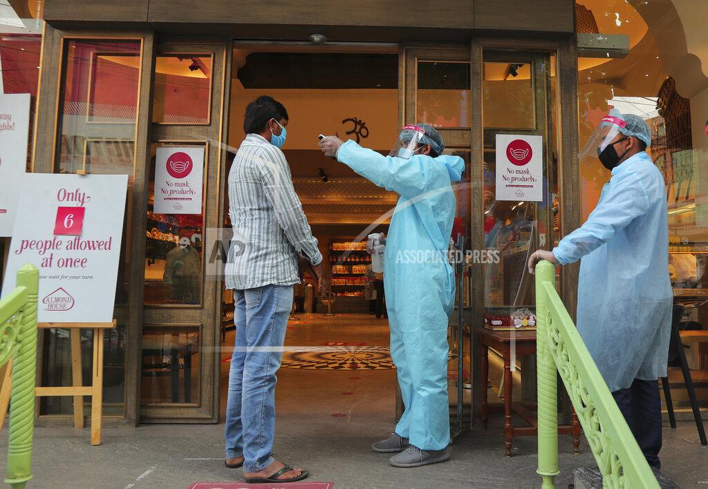 Mahesh Kumar A An Indian security personnel wearing protective gear checks the temperature of a customer before allowing him to enter a sweet shop in Hyderabad, India, Friday, June 5, 2020. The more than two-month-old lockdown is now largely being enforced only in high-risk areas, known as containment zones. The government has partially restored train service and domestic flights and allowed the reopening of shops and manufacturing. (AP Photo/Mahesh Kumar A.)