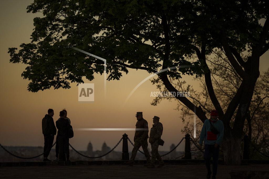Emilio Morenatti Two men from the Ukrainian territorial defence forces patrol at a public park as the sun sets in Kyiv Ukraine on Tuesday, May 10, 2022. (AP Photo/Emilio Morenatti)