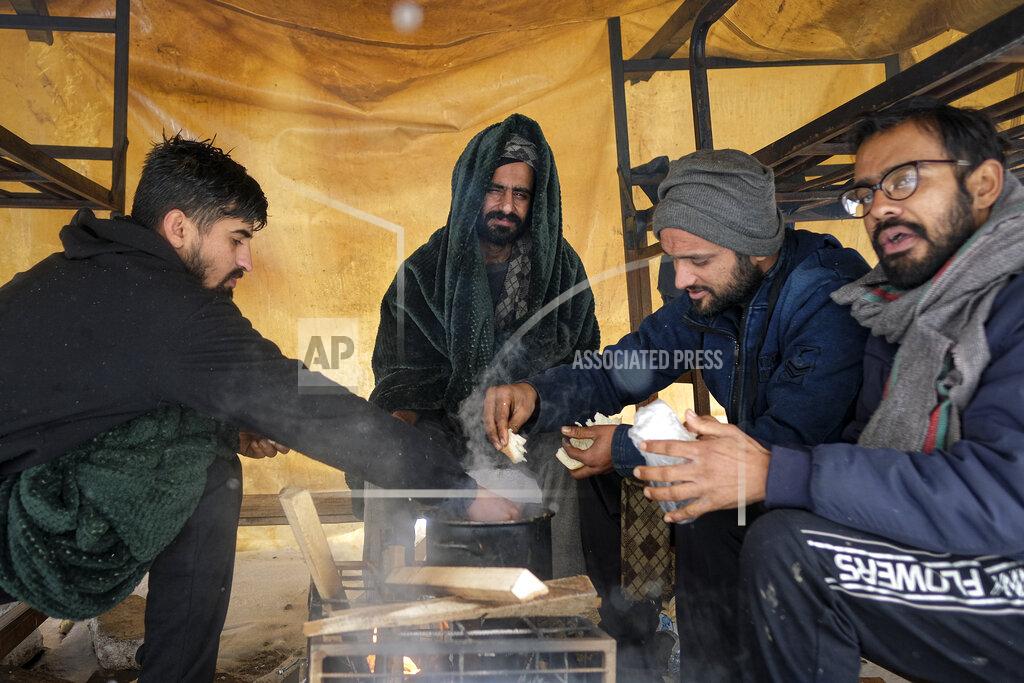 Kemal Softic Migrants eat, at the Lipa camp, outside Bihac, Bosnia, Monday, Jan. 11, 2021. Aid workers say migrants staying at a camp in northwestern Bosnia have complained or respiratory and skin diseases after spending days in make-shift tents and containers amid freezing weather and snow blizzards. Most of the hundreds of migrants at the Lipa facility near Bosnia's border with Croatia on Monday have been accommodated in heated military tents following days of uncertainty after a fire gutted most of the camp on Dec. 23. (AP Photo/Kemal Softic)