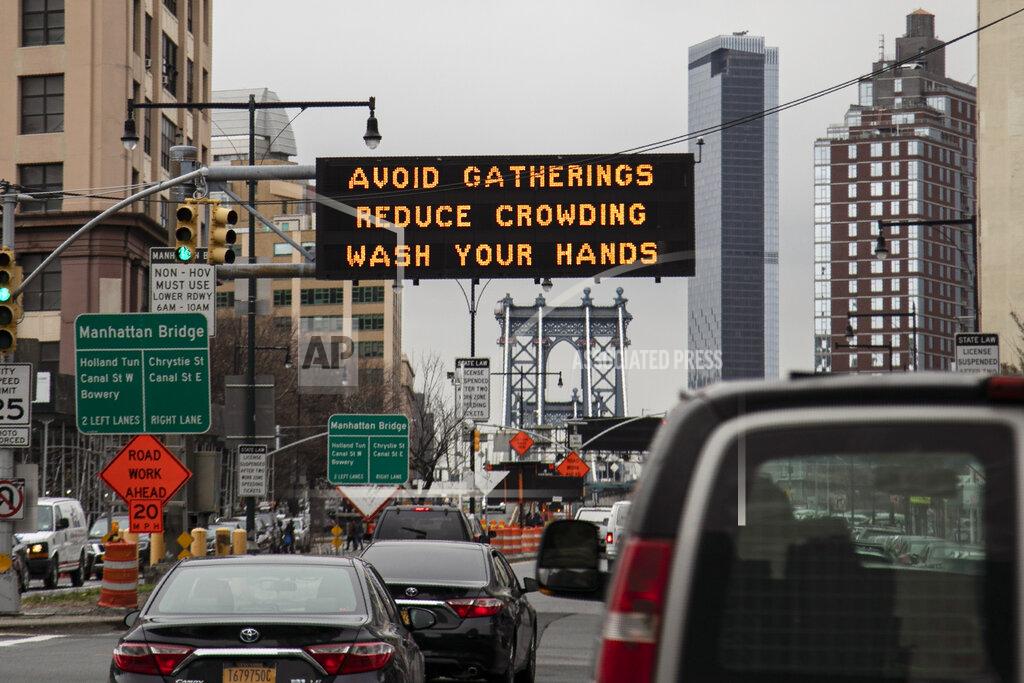 Wong Maye-E FILE - In this Thursday, March 19, 2020 file photo, The Manhattan bridge is seen in the background of a flashing sign urging commuters to avoid gatherings, reduce crowding and to wash hands in the Brooklyn borough of New York. A year after becoming a global epicenter of the coronavirus pandemic, New York and New Jersey are back atop the list of U.S. states with the highest rates of infection.(AP Photo/Wong Maye-E, File)