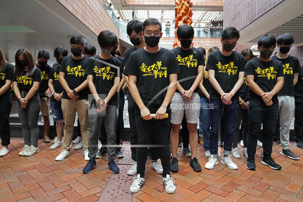 Kin Cheung University students observe one minute silence to mourn those killed in the 1989 Tiananmen crackdown, in front of the "Pillar of Shame" statue at the University of Hong Kong, Friday, June 4, 2021. Police arrested an organizer of Hong Kong's annual candlelight vigil remembering the deadly Tiananmen Square crackdown and warned people not to attend the banned event Friday as authorities mute China's last pro-democracy voices. (AP Photo/Kin Cheung)