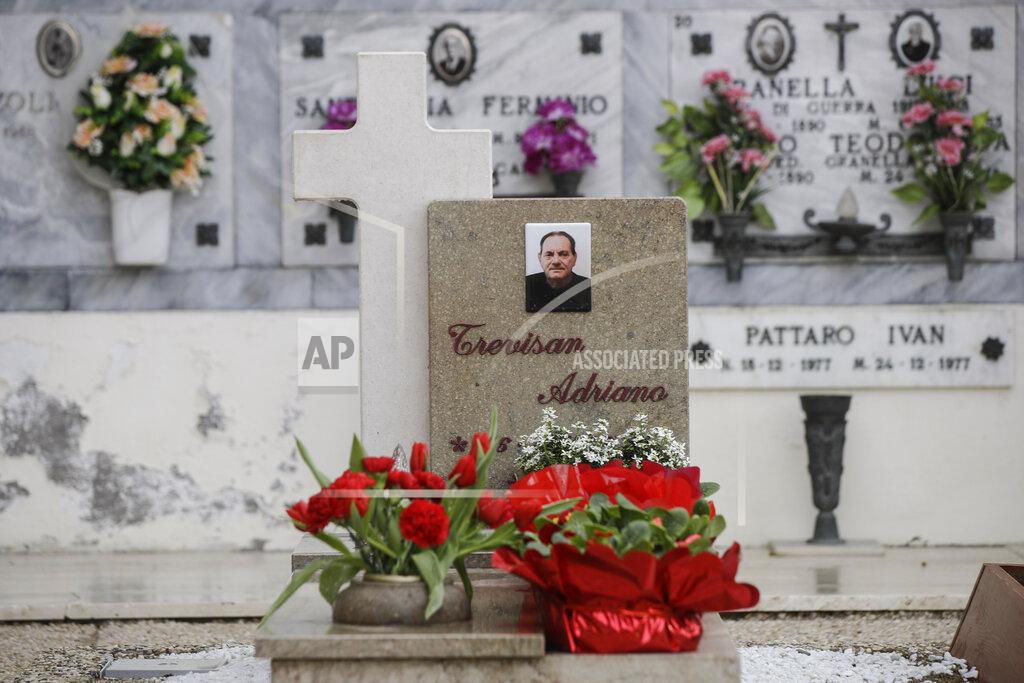 Luca Bruno Flowers adorn the tombstone of Adriano Trevisan, Italy's first known victim of COVID-19, at the cemetery of Vo Vecchio, in Vo Euganeo, Italy, Wednesday, Feb. 10, 2021. Shockwaves ran through the wine-making village of Vo', west of Venice, as word spread last Feb. 21 that a retired roofer had died of the new coronavirus becoming the first known COVID-19 victim in the West. (AP Photo/Luca Bruno)