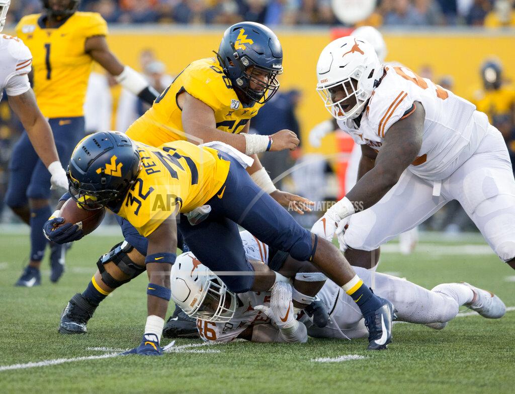 Ray Thompson West Virginia running back Martell Pettaway (32) is tackled by Texas linebacker Joseph Ossai (46) during the second half of an NCAA college football game Saturday, Oct. 5, 2019, in Morgantown, W.Va. (AP Photo/Raymond Thompson)