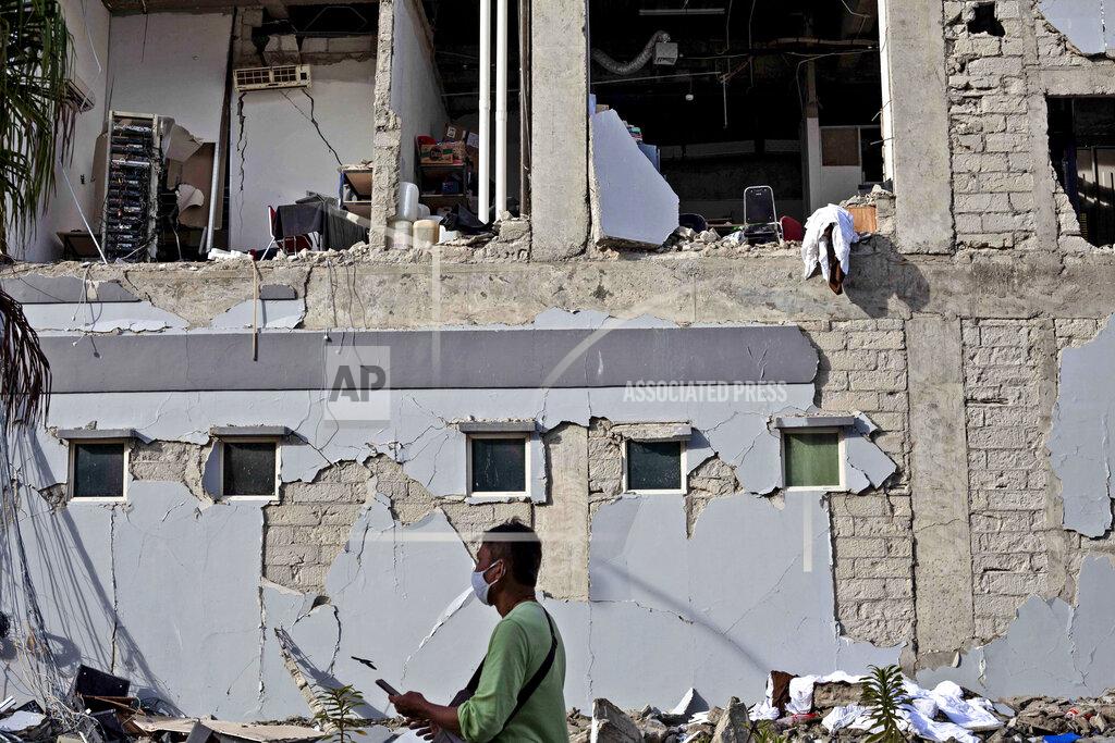 Yusuf Wahil A man walks past a building damaged in Friday's earthquake in Mamuju, West Sulawesi, Indonesia, Monday, Jan. 18, 2021. Aid was reaching the thousands of people left homeless and struggling after an earthquake that killed a number of people in the province where rescuers intensified their work Monday to find those buried in the rubble. (AP Photo/Yusuf Wahil)
