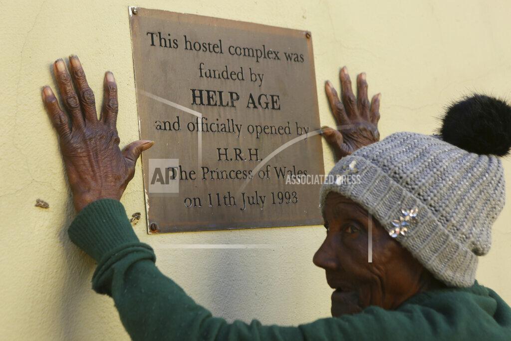 Tsvangirayi Mukwazhi An elderly person stands near a placard at the Society for the Destitute Aged care home in Harare's Highfield township, Zimbabwe, Saturday June, 26, 2021. Princess Diana officially opened an accommodation wing at the home amid much fanfare in 1993. The economic ravages of COVID-19 are forcing some families in Zimbabwe to abandon the age old tradition of taking care of the elderly. Zimbabwe's care homes have experienced a 60% increase in admissions since the outbreak of the pandemic in March last year. (AP Photo/Tsvangirayi Mukwazhi)