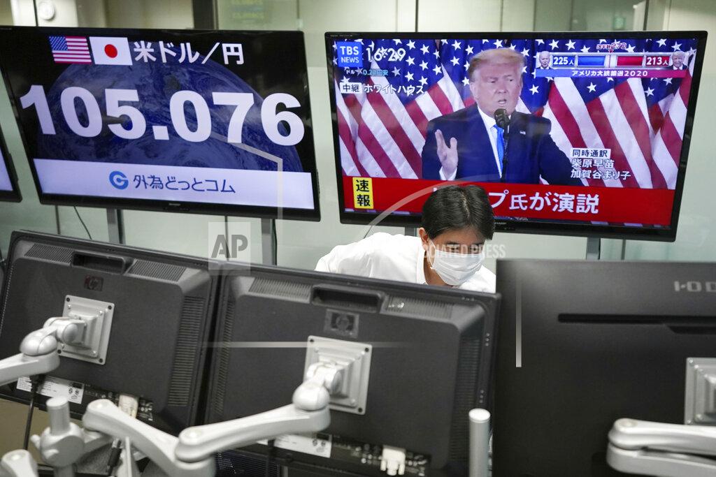 Eugene Hoshiko An employee works near a TV monitor showing a live broadcasting of the press conference by President Donald Trump, at a foreign exchange dealing company Wednesday, Nov. 4, 2020, in Tokyo. (AP Photo/Eugene Hoshiko)