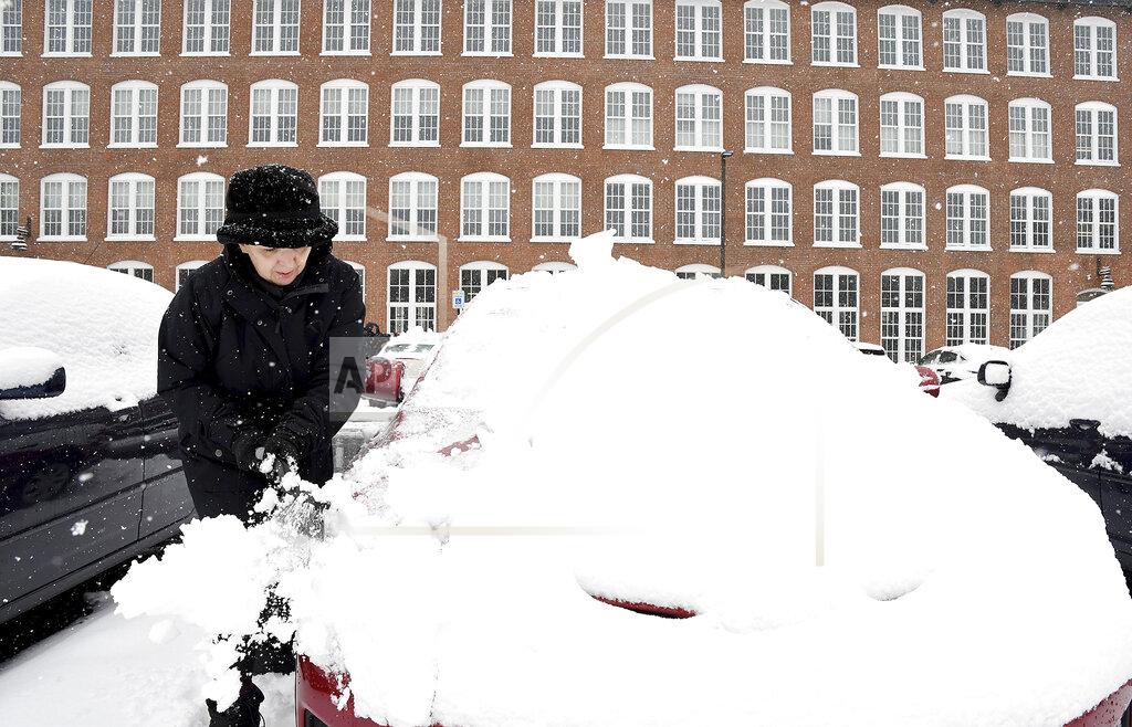 Sue Baker clears snow from her car at the Sterling Lofts apartments Tuesday, Dec. 3, 2019 in Attleboro, Mass. The area received several new inches of snow overnight. (Mark Stockwell/The Sun Chronicle via AP)