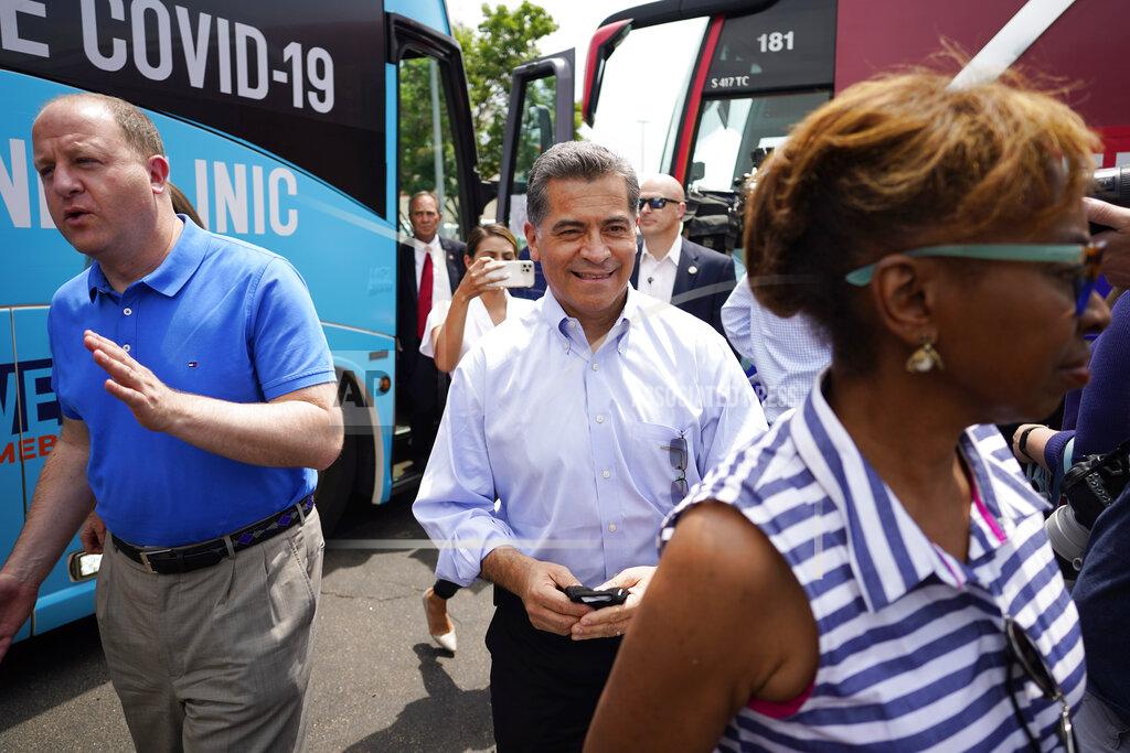 David Zalubowski U.S. Department of Health and Human Services Secretary Xavier Becerra, center, and Colorado Gov. Jared Polis, left, greet well-wishers during a visit to a pair of buses set up as traveling clinics as part of the state's "Vaccines For All" campaign Friday, June 18, 2021, in Aurora, Colo. The buses are being used to distribute COVID-19 vaccines. (AP Photo/David Zalubowski)