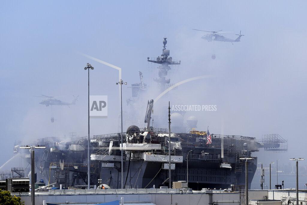 Gregory Bull FILE - In this July 13, 2020 file photo helicopters approach the USS Bonhomme Richard as crews fight the fire in San Diego. The U.S. Navy has decommissioned the USS Bonhomme Richard docked off San Diego nine months after flames engulfed it in one of the worst U.S. warship fires outside of combat in recent memory. The ceremony Wednesday at Naval Base San Diego was not public with the Navy citing concerns over the spread of the coronavirus. (AP Photo/Gregory Bull, File)