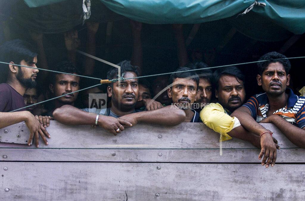 Binsar Bakkara Men from Bangladesh ride in the back of a truck heading to an immigration detention center in Medan, North Sumatra, Indonesia, Wednesday, Feb. 6, 2019. Officials said a few dozen men were found locked in a house, waiting for a broker to bring them illegally by boat to Malaysia, with some planning to work on palm oil plantations. (AP Photo/Binsar Bakkara)